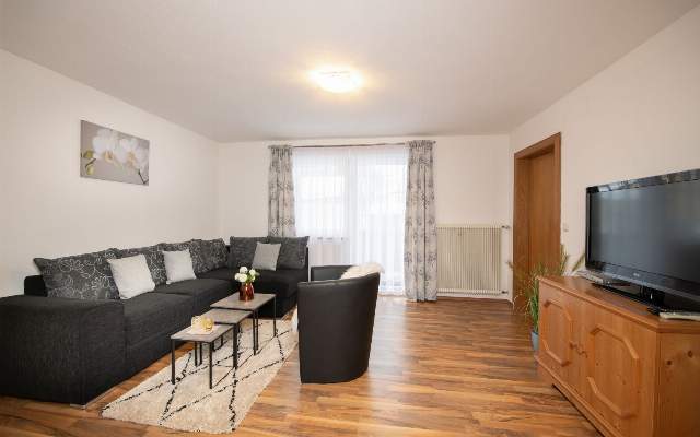 Geräumiges Wohnzimmer mit Flat-TV und Balkon im Appartement