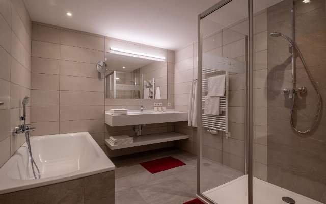 Helles und geräumiges Badezimmer mit Dusche, Badewanne und Handtuchwärmer