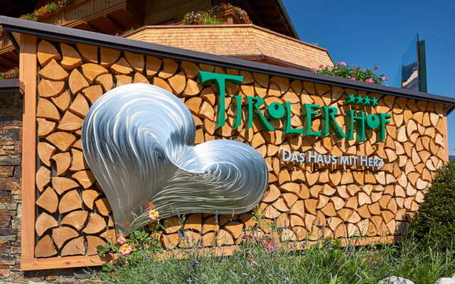 Das Motto des Tirolerhofes mit Logo an einem schoenen Holzstaffel